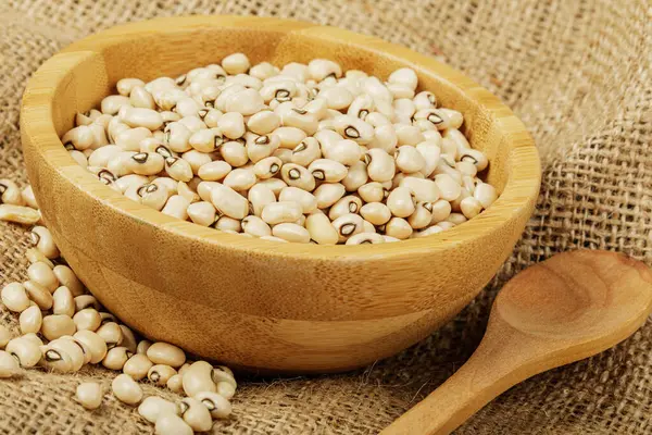 Close up of a wooden bowl of Black Eyed Peas also known as Black Eyed Beans on a canvas background with copy space