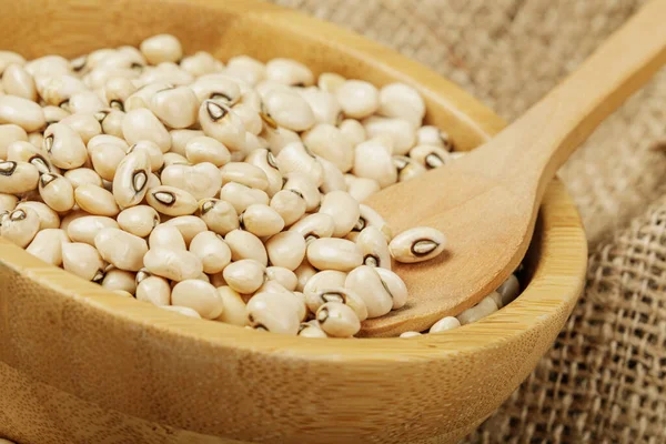 Close up of a wooden bowl of Black Eyed Peas also known as Black Eyed Beans on a canvas background with copy space