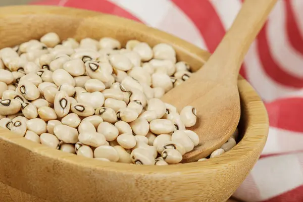 Close up of a wooden bowl of Black Eyed Peas also known as Black Eyed Beans on a wooden background with copy space