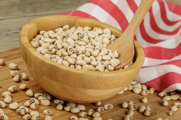 Close up of a wooden bowl of Black Eyed Peas also known as Black Eyed Beans on a wooden background with copy space