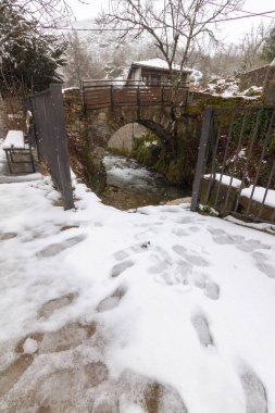 a stone bridge over a river in a snowy mountain town clipart