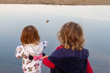 Sakin bir Lakeshore 'da İki Küçük Çocuk Dalgalanmayı İzliyor