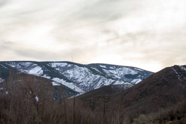 Yükselen karla kaplı dağları olan sakin bir dağ manzarası.