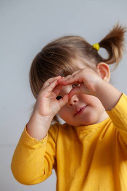 Hayali bir kamerayla fotoğraf çekiyormuş gibi yapan 3 yaşında sevimli bir kız.