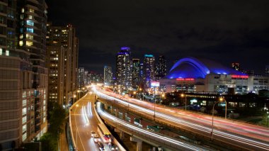 Gardner ekspres yolu Toronto şehir merkezinden batıya gidiyor. Işıklı patikalar ve gece gökyüzü çizgisi var.