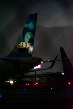 Jet Blue havayolu şirketi gece yarısından hemen sonra kalkış sırasının gelmesini bekliyor. Kuyruğu ışıl ışıl parlıyor. Jet mavisi logosu aydınlanıyor.