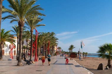 Turistler ve ziyaretçiler 13 Ekim 2022 Perşembe günü güzel güneş ışığı Vinaros, Costa del Azahar İspanya 'da yürüyüş yapıyorlar.