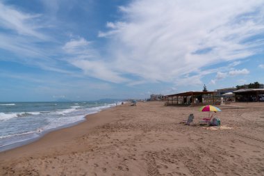 İspanya 'nın Gandia ve Cullera arasında deniz, dalga ve şemsiyeli Xeraco plajı