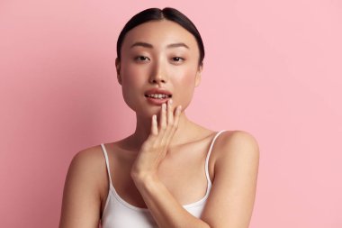 Dudakları Dokunan Şefkatli Kadın. Yüzüne Dokunan ve Gülümseyen Asyalı Kadın portresi. Kadın Görünümü ve Cilt Bakımı 