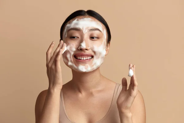 Face Skin Care. Asian Woman Cleaning Facial Skin with Foam Soap. Happy Girl Cleansing Face Applying Facial Cleanser Closeup. High Resolution