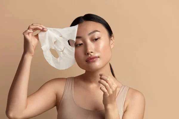 Beauty Woman Face Mask. Portrait Of Beautiful Girl Removing Sheet Mask from Healthy Fresh Skin. Closeup Of Attractive Woman With Natural Makeup And Mask On Facial Skin. High Resolution