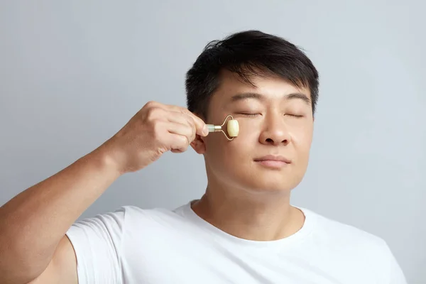 Massagem Facial Homem Asiático Usando Jade Facial Roller Para Cuidados — Fotografia de Stock