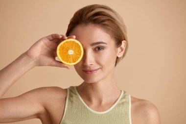 Portakal Meyveli Gülümseyen Güzel Kadın. Parlak Yüzlü Pozitif Kadın Cilt İçin Vitamin Tavsiye Etti. Doğal makyajlı ve parlayan nemli ciltli kız mankeni. C vitamini kozmetik kavramı 