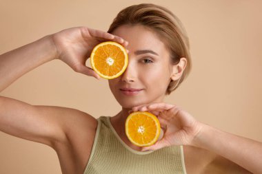 Portakal Meyveli Gülümseyen Güzel Kadın. Parlak Yüzlü Pozitif Kadın Cilt İçin Vitamin Tavsiye Etti. Doğal makyajlı ve parlayan nemli ciltli kız mankeni. C vitamini kozmetik kavramı 