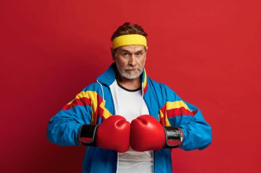 Eldiven Giyen Güçlü Adam. Kıdemli Adam Eğitimi ve Ellerinde Gücünü Gösterme portresi, Yaşındaki Enerjiyi Hissetme. Kapalı Stüdyo Çekimi Kırmızı Arkaplanda İzole Edildi 