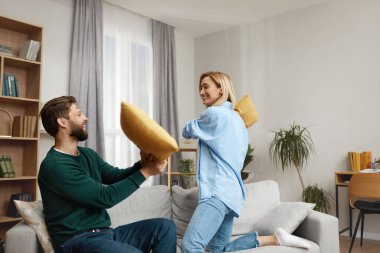 Evde Savaşan Yastıklar. Oturma odasında yastıklarla kavga eden mutlu genç çift. Pozitif Aile Birlikte Eğleniyor 