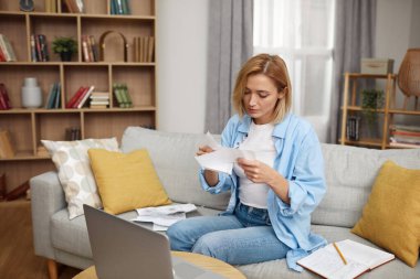 Faturaları Ödeyen Ciddi Kadın. Evde otururken internetteki faturaları hesaplayan ve ödeyen endişeli kadın. Kadın aile bütçesi