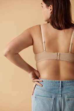 Plus Size Woman. Back View Of Happy Full Figured Woman Posing In Beige Lingerie At Studio. Confident Plus Size Lady Smiling Indoors. Love Yourself Concept 