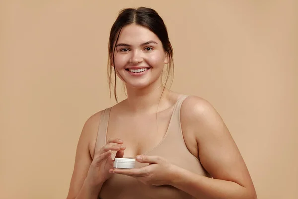 Beauty Woman Holding Face Cream. Closeup Of Female Model With Fresh Skin Posing with Cream Bottle In Hands. Skincare Concept. High Resolution