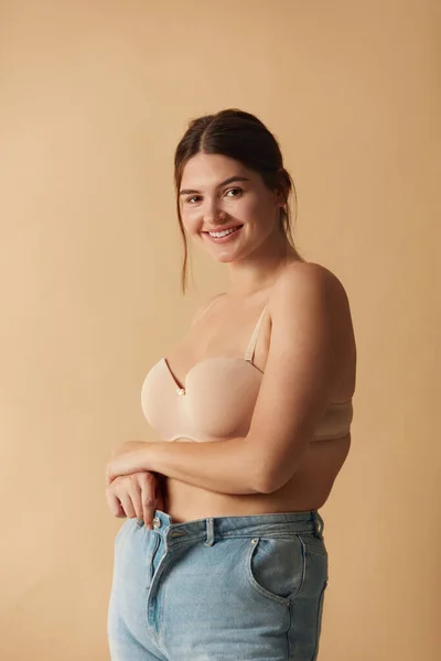 Plus Size Woman in Jeans. Overweight Smiling Woman Demonstrating Weight Loss. Happy Girl Showing Large Jeans And Looking At Camera