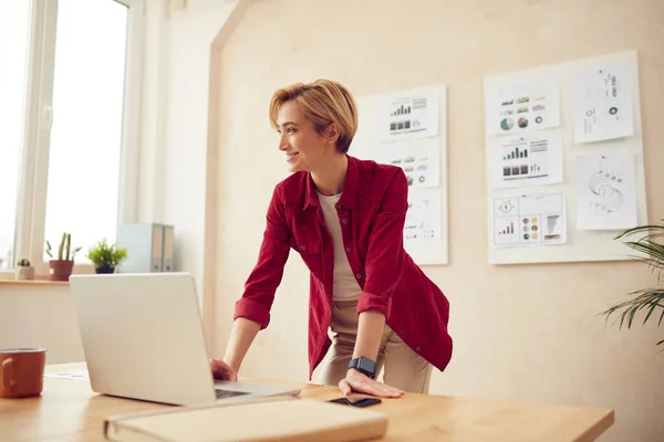 Smiling Woman Standing Office. Positive Businesswoman Looking Away At Workplace. Blonde Lady Working Laptop Pc Computer Indoors