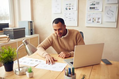 Smiling Businessman Working Office. Positive Guy Examining Documents at Computer Table. Male Person Sitting At Workplace In Modern Office. Career Concept 