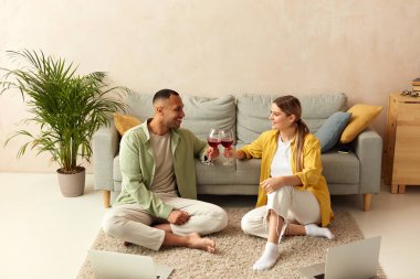 Happy Couple Drinking Wine. Smiling Spouses Holding Wineglasses With Tasty Red Wine at Home. They Are Smiling And Drinking Their Drinks. Date And Love Concept 