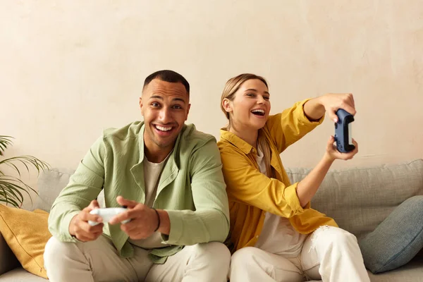 快乐伴侣玩电子游戏 男朋友和女朋友坐在客厅的长椅上 享受电子游戏 共度时光 享受周末快乐时光的概念 — 图库照片