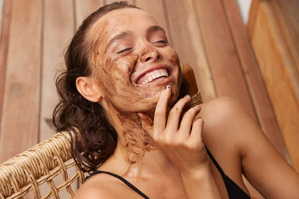 Face Care. Smiling Young Woman With Natural Makeup And Coffee Scrub Mask On Fresh Facial Skin. Portrait Of Beautiful Sexy Female Model With Peeling Cosmetic Product On Beauty Face