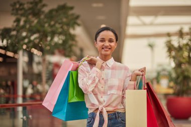 Alışveriş merkezinde poşet tutarken gülümseyen bir kadın. Moda alışveriş çılgınlığının tadını çıkarıyorum..