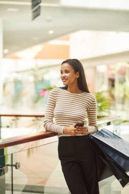 Bir hafta sonu moda bir butikte beklerken gülümseyen genç bir kadın. O indirimli indirimli giysiler almaktan mutlu..