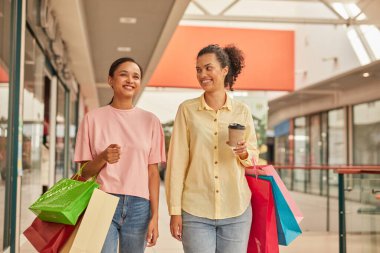 Alışveriş merkezlerinde alışveriş torbalarıyla gezen iki mutlu insan, birlikte şık bir alışveriş hayatının tadını çıkarıyorlar..