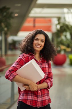 Kıvırcık saçlı, gülümseyen ve hafta sonunu alışveriş merkezinde geçiren bir kadın..
