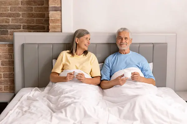 Happy Senior Couple Sitting Drinking Coffee Talking Together Bed — Stock Photo, Image
