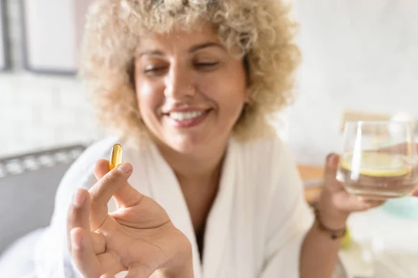 Joyful Woman Cozy White Bathrobe Holds Yellow Supplement Capsule Take — Stock Photo, Image
