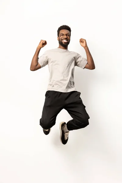 Energetic African American Man Casual Attire Leaping Joyfully White Studio — Stock Photo, Image