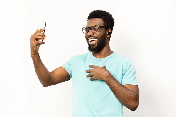 Šťastný Afroameričan Neformálním Oblečení Pomocí Smartphonu Sluchátek Izolovaný Bílém Pozadí — Stock fotografie