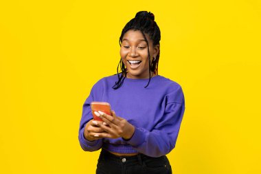 Parlak sarı arka planda akıllı telefon kullanan bir kadın..