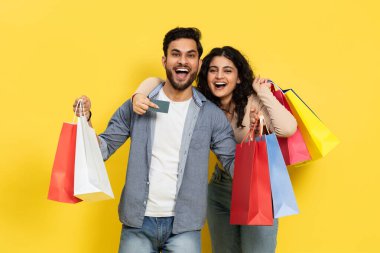 Gülümseyen ve renkli alışveriş torbaları tutan bir çift ve bir kredi kartı, tüketiciliği, satışı ve Joy 'u örnek alıyor. Modern alışveriş deneyimlerinin heyecan ve çeşitliliğini yansıtmak için mükemmel..