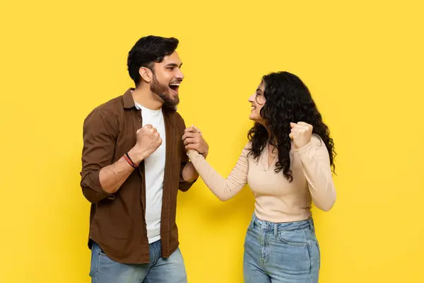 Energetic Young Couple Fist Pumping Merayakan Sukses Latar Belakang Kuning — Stok Foto