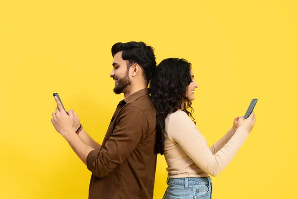 Pasangan Berdiri Kembali Belakang Menggunakan Smartphone Pada Latar Belakang Kuning — Stok Foto