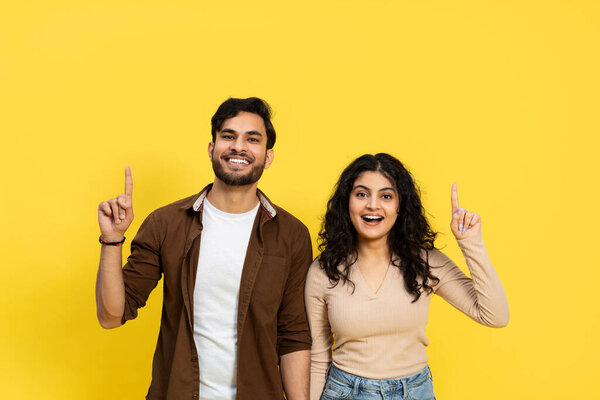Two People Pointing Up In Casual Clothing Against Yellow Background, Concept Of Idea And Teamwork
