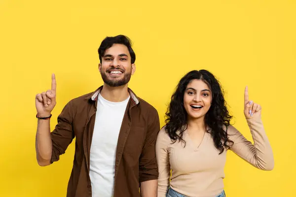 Happy Couple Pointing Upwards Yellow Background Smiling Young Adults Positive — Stok Foto