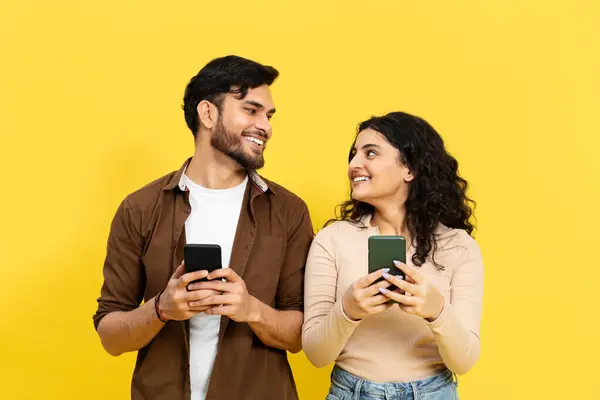 Young Couple Engrossed Smartphone Yellow Background Communication Social Media Dalam — Stok Foto