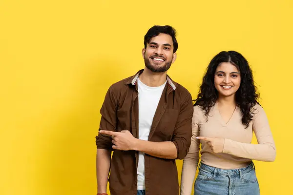 Pasangan India Menunjuk Dan Senyum Menentang Latar Belakang Kuning Pakaian — Stok Foto
