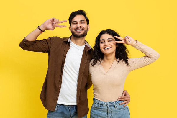 Happy Couple Making Peace Sign With Bright Yellow Background, Joyful Expression, Positive Vibes