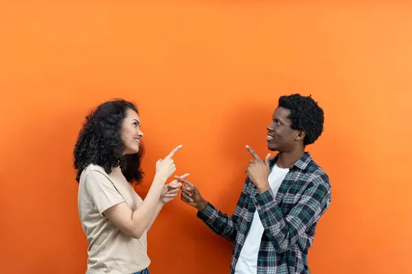 オレンジの背景が付いている幸せな多民族のカップルの指 現代の多様な関係 陽気な若者は笑っている カジュアルウェア 混血した民族の友情 コミュニケーション コンセプト ストックフォト