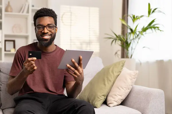 Lächelnder Mann Mit Kreditkarte Und Tablet Hause Fröhlicher Junger Afroamerikanischer Stockbild