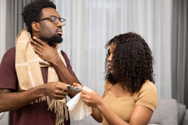 Boğazı ağrıyan hasta bir adam bir kadından bakım alıyor, evde boğaz pastilleri veriyor.