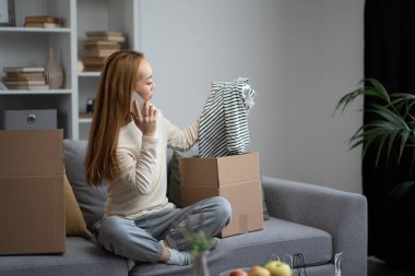 Genç bir kadın, koltukta otururken mutlu ve rahat hissediyordu. Çevrimiçi Alışveriş ve Ev Hayatı kavramı.